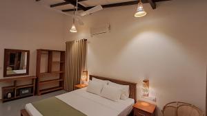 a bedroom with a bed and a television and lights at The Clouds Ahangama in Ahangama