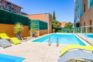- une piscine avec des chaises jaunes à côté d'un bâtiment dans l'établissement Aparthotel Adagio Access Toulouse Jolimont, à Toulouse