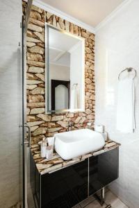 La salle de bains est pourvue d'un lavabo et d'un miroir sur un mur en pierre. dans l'établissement Tropical Oasis-Luxury Apartment, à Trevallyn