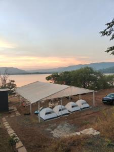 The Lake Story - Uksan في Somavadi: خيمة بها كراسي تحتها بجوار بحيرة