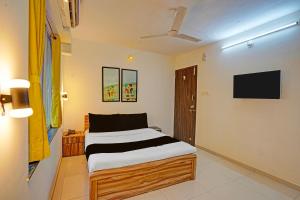 a bedroom with a bed and a flat screen tv at Collection O Baner Hillview Pune Formerly Siri Lodge in Méribel Village