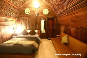 a bedroom with two beds and a couch and clocks at Bukit Delapan Glamping & Coffee in Kubupenlokan