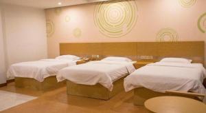 GreenTree Inn Qingdao Jiaozhou Jiaoping Road Express Hotel في Jiaoxian: ثلاثة أسرة في غرفة ذات أغطية بيضاء