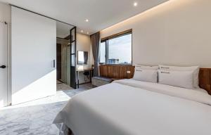 群山市Gunsan LAONHAJE的卧室里有一张白色的床和一扇大窗户