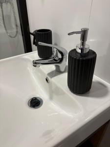 a bathroom sink with a black soap dispenser on it at KE-Tiny Haus Paulchen in Oerlenbach +24 photos