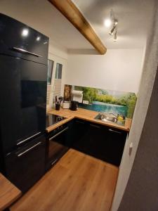 Una cocina con un refrigerador negro y un fregadero. en Bei GRETA 33, en Marl