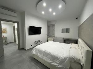Un dormitorio con una cama blanca y un televisor de pantalla plana. en Milano Bicocca Apartment & Rooms2, en Cinisello Balsamo