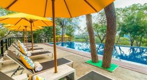 a pool with chairs and umbrellas and a swimming pool at Elephant Stables Dambulla in Kiralagolla +16 photos