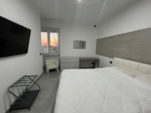 Un dormitorio blanco con una cama grande y un televisor. en Milano Bicocca Apartment & Rooms2, en Cinisello Balsamo