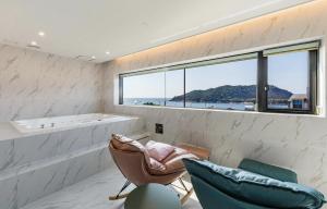 群山市Gunsan LAONHAJE的一间带浴缸的浴室和窗户前的两把椅子