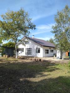 a white house with a tree in front of it at プチキャンプ場おちぼの郷 in Furano