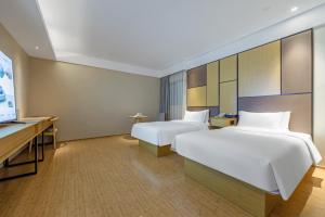 a hotel room with two beds and a flat screen tv at JI Hotel Shanghai Changshou Road in Shanghai +20 photos