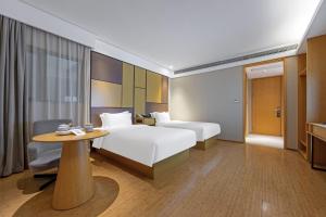 a hotel room with two beds and a table at JI Hotel Shanghai Changshou Road in Shanghai