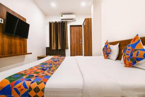 a bedroom with a large white bed with a flat screen tv at FabHotel Apple Near ITI in Indore