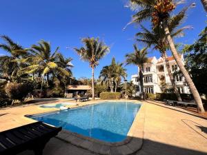 a swimming pool in front of a house with palm trees at Bazaar Square Lodges in Grand-Baie