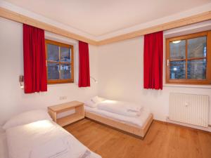 Un dormitorio con dos camas y cortinas rojas. en Apartment in Wald im Pinzgau with Swimming Pool and Views, en Wald im Pinzgau