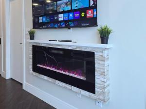 a fireplace with a tv on top of it at Family Stylish 2BR Condo with City View, DT, Balcony, Free Parking & In-Suite Laundry! in Calgary