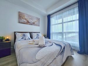 a bedroom with a bed and a large window at Family Stylish 2BR Condo with City View, DT, Balcony, Free Parking & In-Suite Laundry! in Calgary