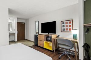 a hotel room with a bed and a desk with a television at Spark by Hilton Portland Airport Maine Mall in South Portland