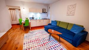a living room with a blue couch and a kitchen at Park Sportowy, Sun & Snow in Krynica Zdrój