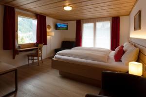 una camera d'albergo con un letto, una scrivania e una finestra di Hotel Hirschen - Grindelwald a Grindelwald Altre 122 foto