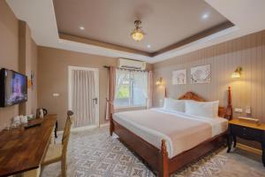 a bedroom with a bed and a desk and a television at Perennial Resort in Nai Yang Beach