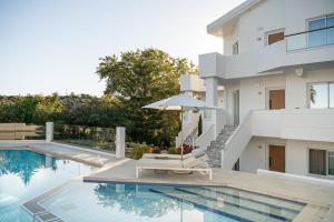 una piscina con sedia e ombrellone accanto a una casa di Villa Life ad Agia Marina Nea Kydonias