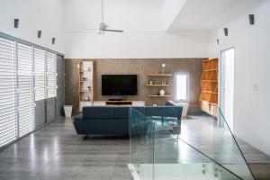Villa Mariposa Ocean Front Mansion with Infinity Pool في غانيكا: غرفة معيشة مع أريكة زرقاء وتلفزيون