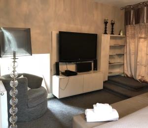 a living room with a television and a chair at The Oaks A private room in our home With its own entrance with internal doors locked More suited to quieter guests wanting a peaceful stay in Consett
