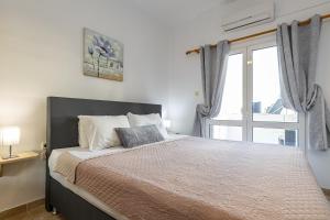 a bedroom with a large bed with a window at Panoramio Paleochora Apartments in Palaiochóra +96 photos