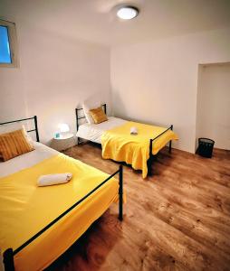 two beds with yellow sheets in a room with wooden floors at La maison du château in Saint-Victurnien +3 photos