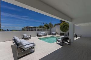 een patio met ligstoelen en een zwembad bij L X I Camps Bay in Kaapstad