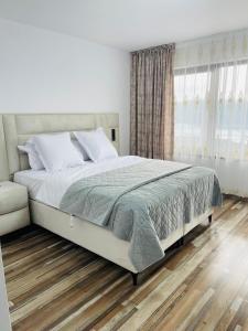 Un dormitorio blanco con una cama grande y una ventana. en Pensiunea La Vio, en Grozavesti