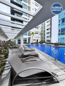 een rij ligstoelen naast een zwembad bij Relax Stay at One Madison Tower in Cari Mayor