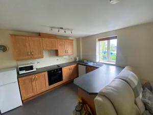 a kitchen with wooden cabinets and a couch at Friars terrace in Stafford