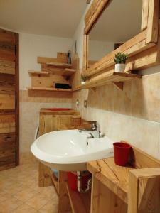 y baño con lavabo blanco y armarios de madera. en Botton d'oro, en Campitello di Fassa