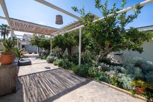a garden with a pergola and trees and plants at Villa Arancia Private Pool, 2 Jacuzzis & BBQ Area in Pigi
