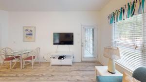 a living room with a table and a tv at Club Villas Unit 17D - Lower Level in Sunset Beach