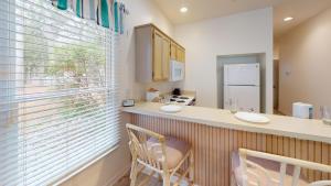 a kitchen with a counter with two chairs and a window at Club Villas Unit 17D - Lower Level in Sunset Beach