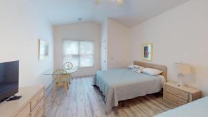 a bedroom with a bed and a table and a tv at Club Villas Unit 17D - Lower Level in Sunset Beach