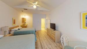 a bedroom with two beds and a flat screen tv at Club Villas Unit 17D - Lower Level in Sunset Beach