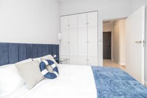 ein Schlafzimmer mit einem weißen Bett und einem blau-weißen Kissen in der Unterkunft Apartament Heaven Hampton in Olsztyn