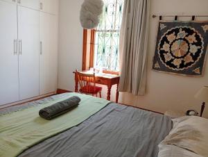 een slaapkamer met een bed, een tafel en een raam bij Victorian Woodstock in Kaapstad +27 foto's