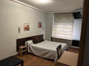 a small bedroom with a bed and a window at Hostal Conde David in Salamanca