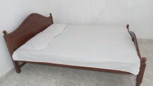 a bed with a wooden frame in a room at New Moon in Pannipitiya