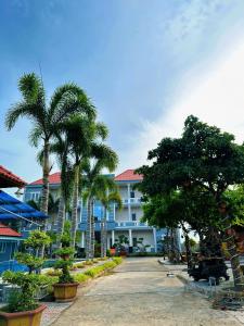 a building with palm trees in front of it at Ven Song Riverside Hotel in Ho Tram