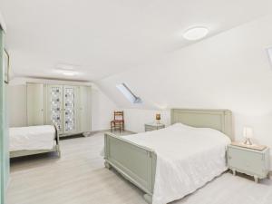 a white bedroom with two beds and a window at Maison pour 7 avec jardin - Quartier paisible in Plouguerneau