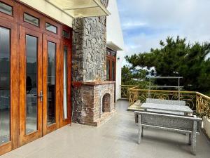 a patio with a stone fireplace and a bench at Khu ngỉ dưỡng Tâm Anh Đà Lạt in Ấp Man Ling +6 photos