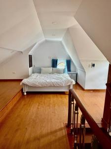 a bedroom with a white bed in a attic at Khu ngỉ dưỡng Tâm Anh Đà Lạt in Ấp Man Ling