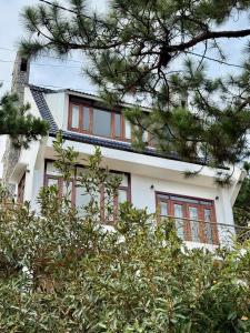 a white house with windows and trees at Khu ngỉ dưỡng Tâm Anh Đà Lạt in Ấp Man Ling